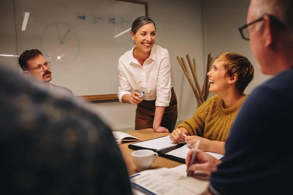 Smiling businesswoman sharing her ideas with team in meeting. Manager leading a meeting in office boardroom.